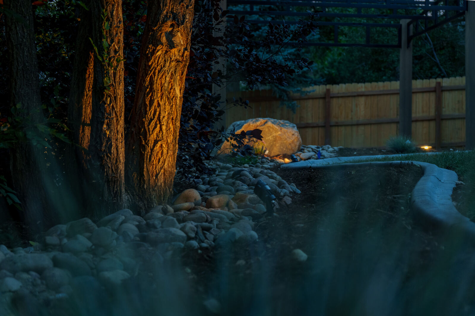 Backyard water feature with boulders at dusk